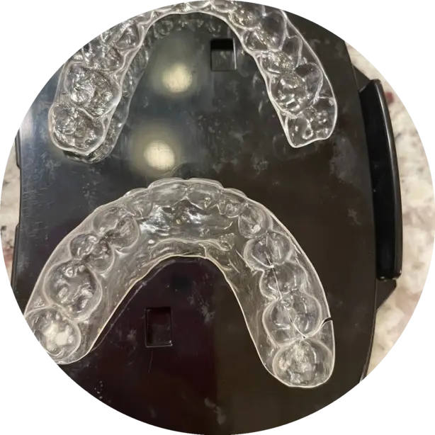 Two clear dental retainers on a black background