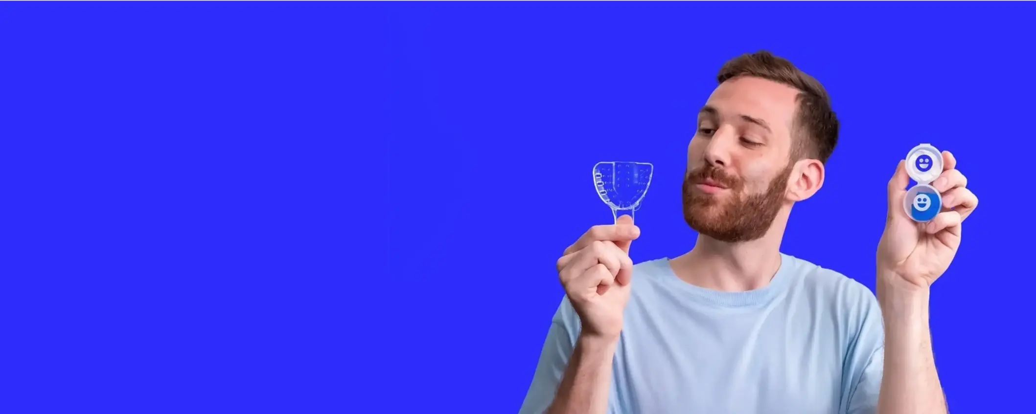 Man holding two dental tools against a blue background
