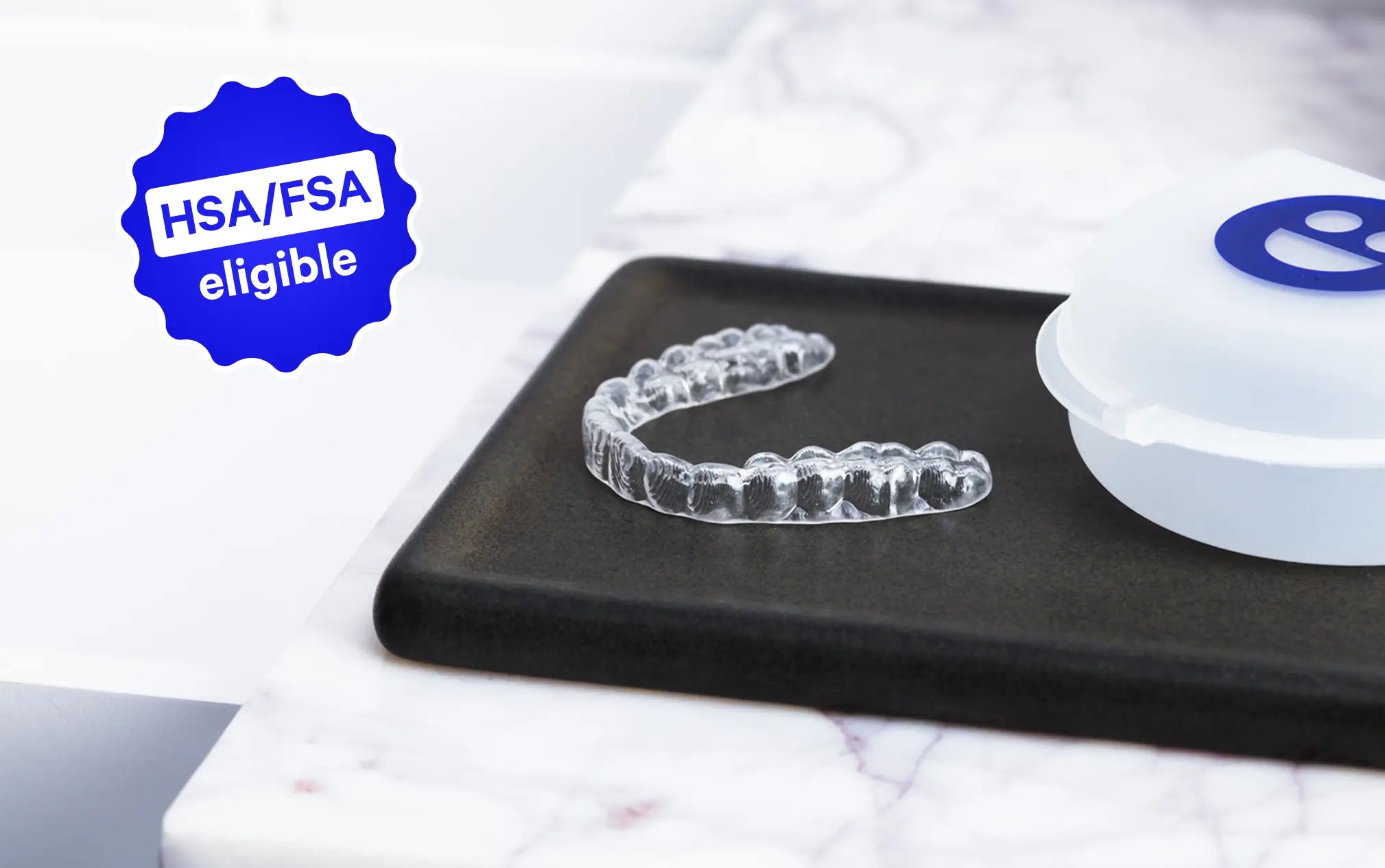 Clear dental aligner on a black tray with a white container on a marble surface, HSA/FSA eligible badge visible.