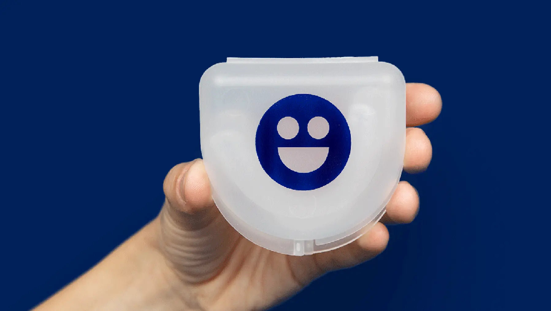 Clear plastic case with a blue smiley face logo held by a hand against a dark blue background
