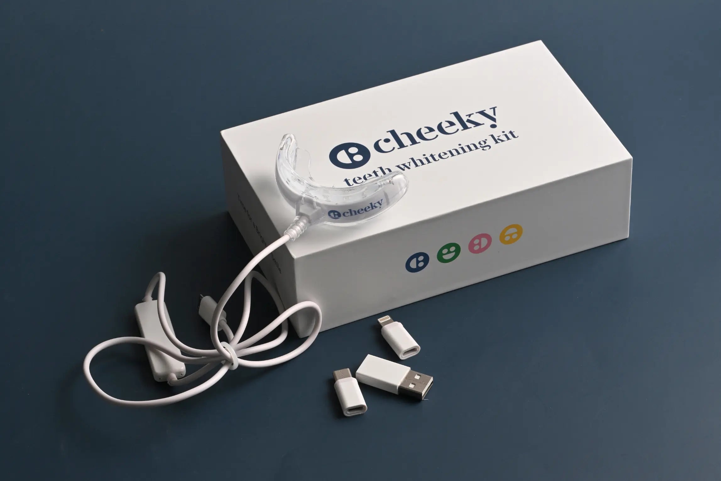 Cheeky teeth whitening kit with packaging on a dark background